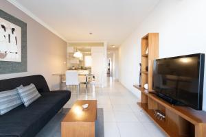 a living room with a black couch and a flat screen tv at AT Suites in Córdoba