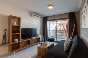 a living room with a couch and a television at AT Suites in Córdoba