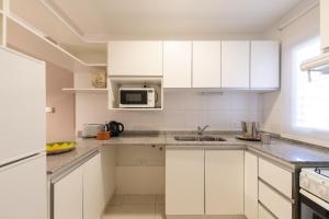 a white kitchen with white cabinets and a sink at AT Suites in Córdoba