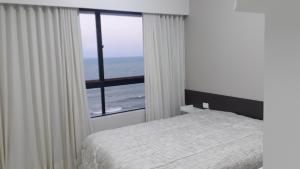 um quarto com uma cama e vista para o oceano em Flat Mercure Família 5pessoas no Recife