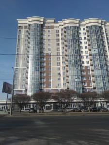 un grand bâtiment de grande hauteur avec des voitures garées devant lui dans l'établissement Апартаменти Люкс, à Khmelnytsky