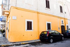 une voiture garée devant un bâtiment jaune dans l'établissement Cuorcuoredicasa, à Monopoli
