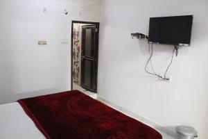 a bedroom with a bed and a flat screen tv at Sunset Backpackers Hostel in Orchha