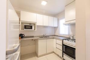 a white kitchen with a sink and a microwave at AT Suites in Córdoba