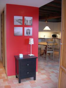 Habitación con pared roja y mesa con lámpara. en Gîte La Penhatière en Baulon