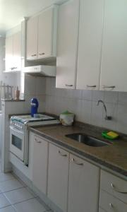 eine Küche mit weißen Schränken und einem Waschbecken in der Unterkunft condominio palmeiras in Ubatuba