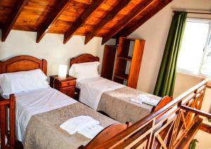 Habitación de hotel con 2 camas y balcón en Cabañas Brisas del Cerro en Los Reartes
