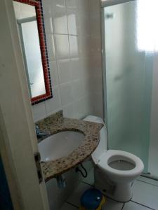 ein Badezimmer mit einem Waschbecken, einem WC und einem Spiegel in der Unterkunft condominio palmeiras in Ubatuba