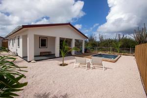 a small white house with two chairs and a pool at Kas Honkie Tonkie in Kralendijk