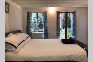 a bedroom with a large bed with two windows at Karma Cottage in Maleny