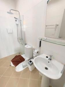 a white toilet sitting next to a sink in a bathroom at Bann Tawan Hostel & Spa in Chiang Rai