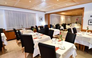 a dining room with white tables and black chairs at Elite in Zermatt