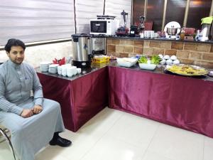a man sitting in a chair in front of a counter at Juniper House in Wadi Musa