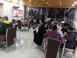 a group of people sitting at tables in a restaurant at Juniper House in Wadi Musa