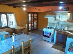 cocina con mesa y fogones horno superior en Hostel Casona Alameda en El Bolsón