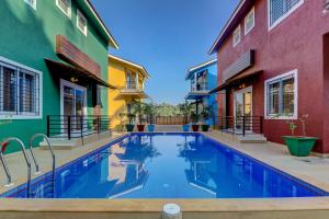 a swimming pool in the middle of two buildings at JAQK Holidays - 9BHK Villa for Big Groups, Private Pool-WiFi-Cartaker-Parking, North Goa in Baga
