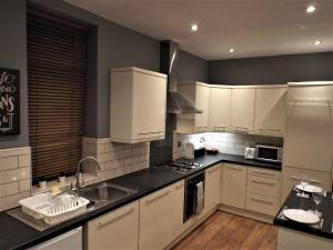 a kitchen with white cabinets and a sink in it at Bronte Cinema Cottage At Haworth in Haworth
