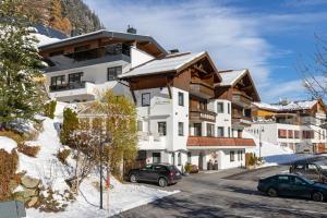 a building in the snow with cars parked in front at Appartements Kardona in Ischgl