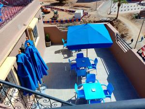 a balcony with blue tables and chairs and umbrellas at hotel arganier tafraoute in Tafraout