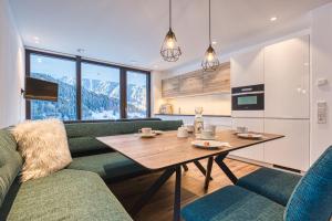 a living room with a green couch and a table at Alpin Apart Montafon in Sankt Gallenkirch