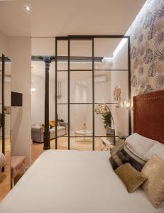 a bedroom with a large white bed and a living room at MIMA Suites Chueca in Madrid