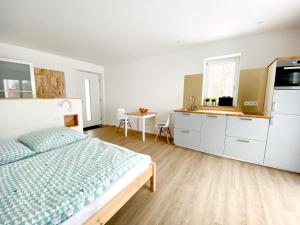 a white bedroom with a bed and a kitchen at AllgäuLiebe in Oy-Mittelberg