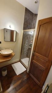 a bathroom with a shower and a sink and a wooden door at VANILLE CAFE CHOCOLAT in Bagnères-de-Bigorre
