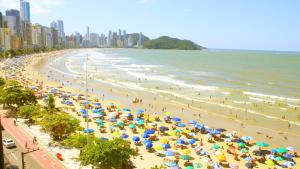 una playa con muchas sombrillas y gente en ella en Totalmente de Frente ao Mar, en Balneário Camboriú