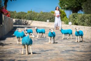 Happy Cretan Suites في أغيا بيلاغيا: امرأة تقف بجوار مجموعة من الأغنام الزرقاء