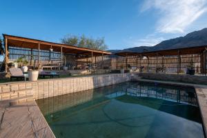ein Swimmingpool mit Terrasse und Bergen im Hintergrund in der Unterkunft 360on62 Farm Cottages in Montagu