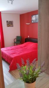 a bedroom with a red bed and a potted plant at La Roseraie in Épinal
