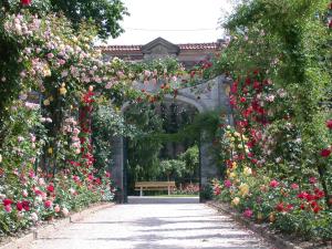 un arco con flores y un banco en un jardín en La Roseraie, en Épinal