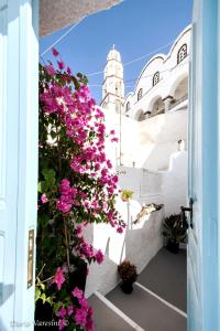 a balcony with pink flowers on a white building at Santorinian Lava House in Pyrgos