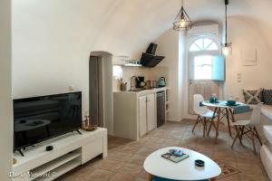 a living room with a large television and a table at Santorinian Lava House in Pyrgos