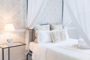 a white bed with white pillows and a table with a lamp at Green Room in Aversa