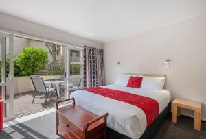 a bedroom with a bed and a balcony with a table at The Village Resort in Taupo