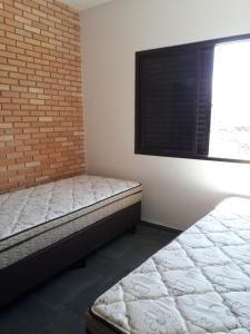 a bedroom with a bed and a brick wall at APARTAMENTO PRAIA CENTRO in Ubatuba