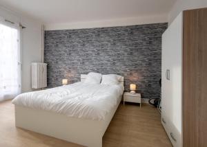 ein Schlafzimmer mit einem weißen Bett und einer Ziegelwand in der Unterkunft Appart'Hôtel de la Gare in Montbéliard