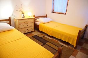- 2 lits dans une chambre avec des draps jaunes et une commode dans l'établissement Apartments Ana - sea view;, à Zavala