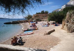 un groupe de personnes sur une plage près de l'eau dans l'établissement Apartments Ana - sea view;, à Zavala