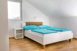 biała sypialnia z łóżkiem z niebieskimi poduszkami w obiekcie Apartments Kula w mieście Janjina