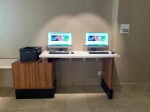 dos monitores de ordenador en un escritorio en una habitación en Holiday Inn Los Angeles - LAX Airport, an IHG Hotel, en Los Ángeles