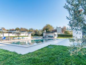 Beautiful Villa in Vrsar with Swimming Pool في فيرسار: مسبح وكراسي ومنزل