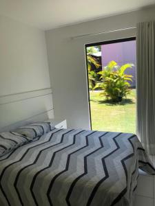 1 dormitorio con 1 cama grande y ventana grande en Itacimirim - Quinta das Lagoas Residence, en Itacimirim