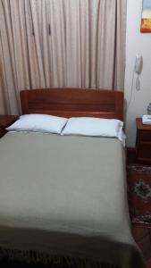 a bedroom with a bed with a wooden headboard at Hostal Santa María Gracia in Quito