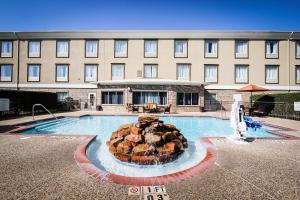 una piscina de hotel con una fuente frente a un edificio en Holiday Inn Express Hotel & Suites Nacogdoches, an IHG Hotel en Nacogdoches