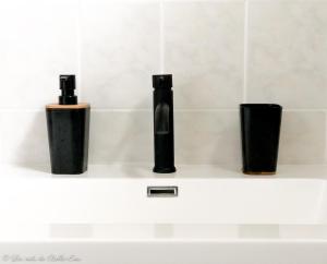 three black vases sitting on a shelf in a bathroom at Les Nids de Belle Eau 1 gîte sur 2 avec jacuzzi in Capesterre-Belle-Eau