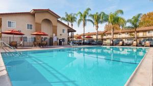 a large pool with chairs and umbrellas next to a hotel at Best Western Plus Ontario Airport & Convention Center in Ontario