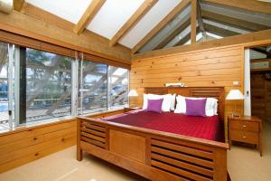 a bedroom with a large wooden bed with purple pillows at Waterfront on Witta Circle in Noosa Heads