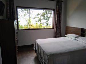 a bedroom with a bed and a large window at Chalé da Katia in Ilhabela